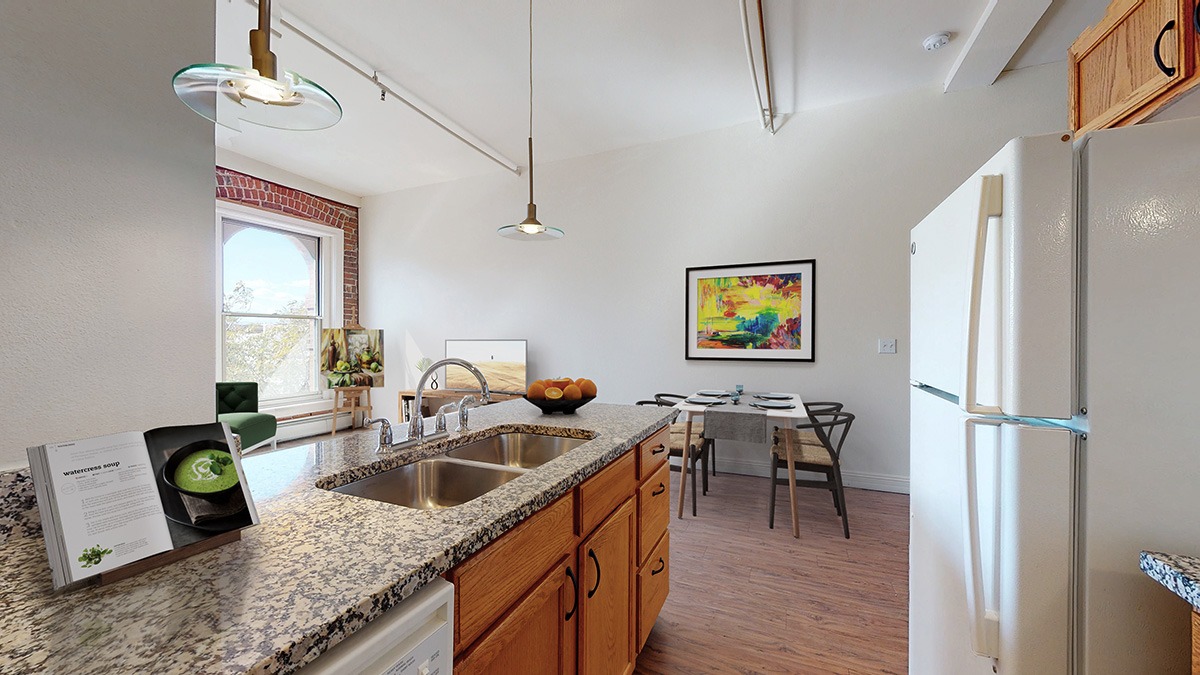 A kitchen with a refrigerator, sink, and a dining table with chairs.