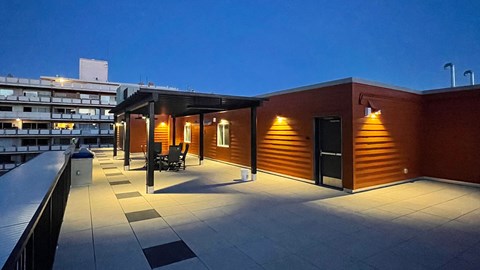 a rooftop terrace at night with a bar and a building