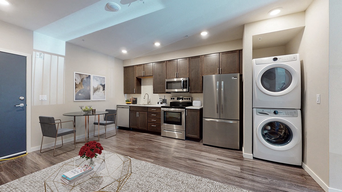 a kitchen with stainless steel appliances and a washer and dryer and a table