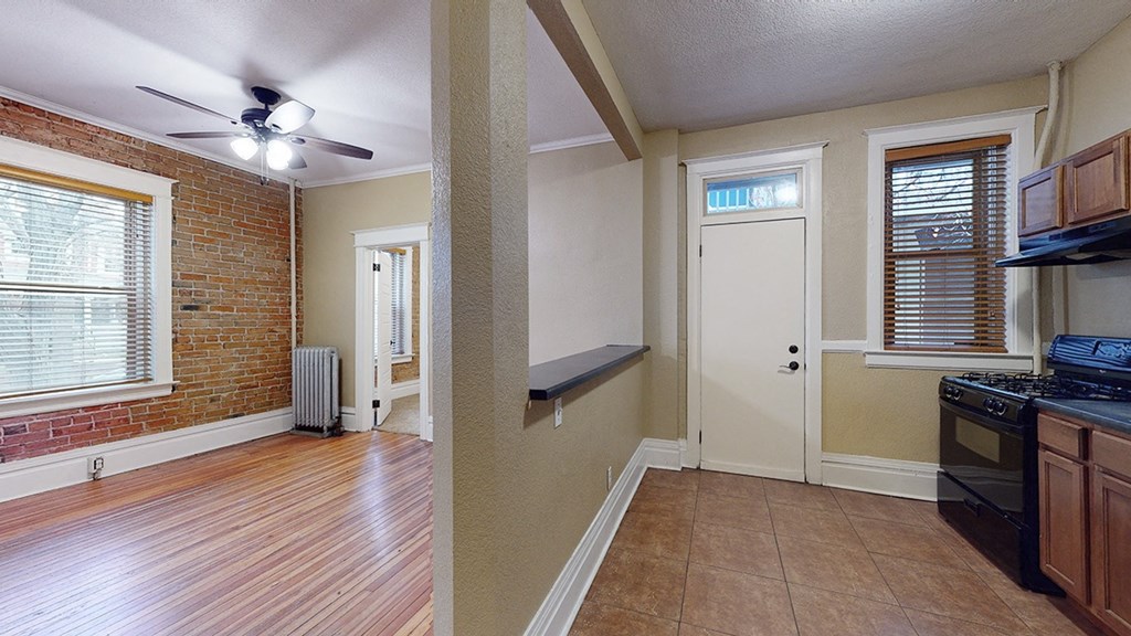 an empty kitchen and living room with a brick wall and wood floors