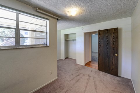 an empty living room with a large window and a door to a bedroom