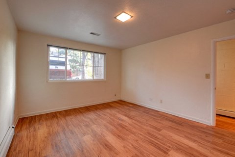 an empty living room with wooden floors and a window