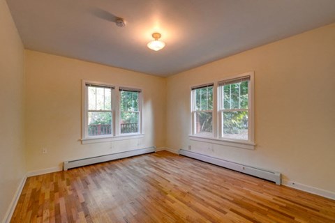an empty living room with a wood floor and three windows
