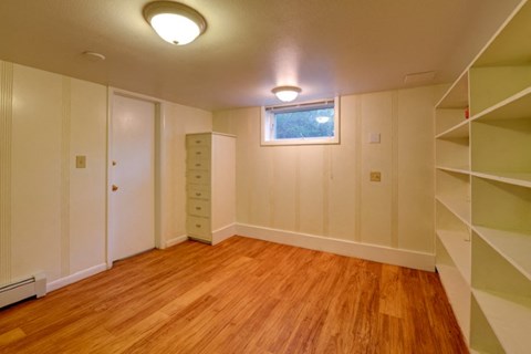 a room with a wooden floor and white shelves