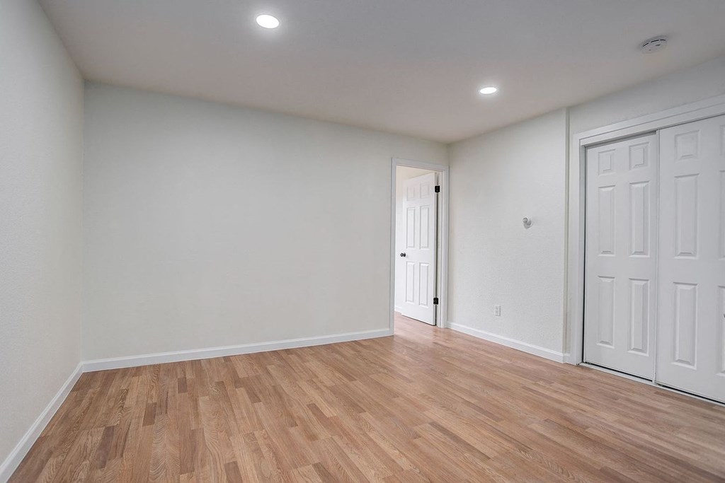 an empty living room with white walls and wood floors