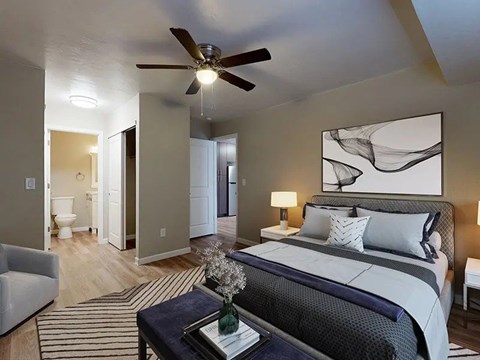 A bedroom with a bed, a chair, a table and a painting on the wall.