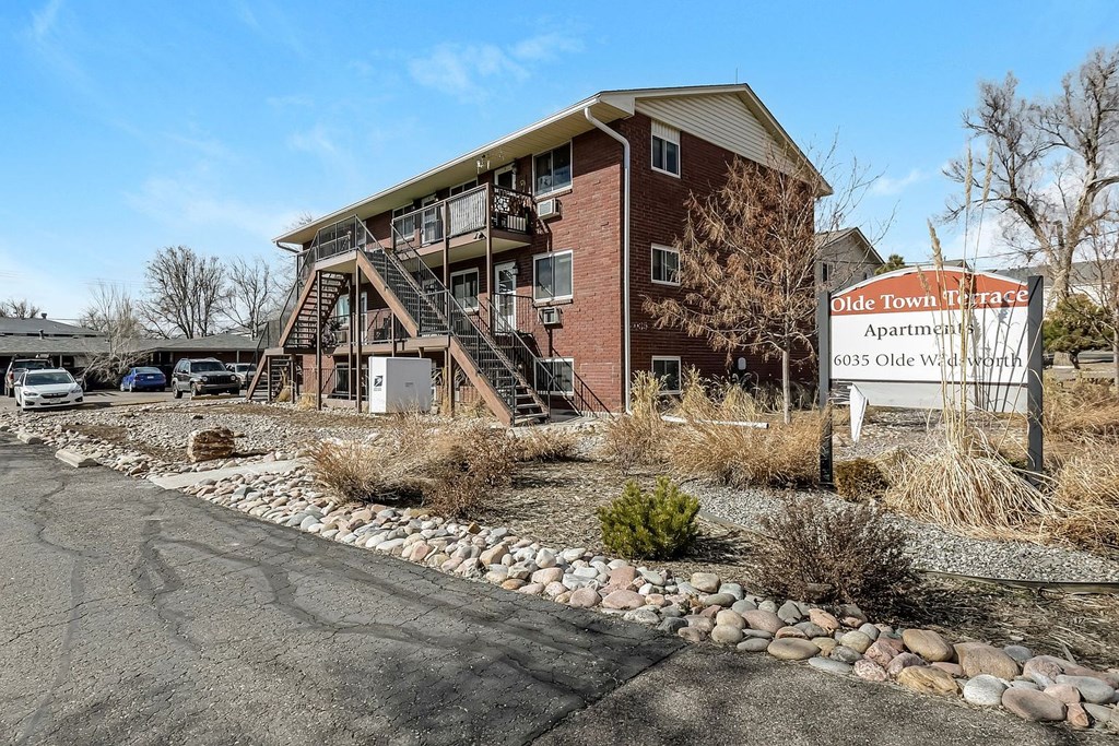A large brick building with a sign that says "Olde Town Apartments" in front of it.