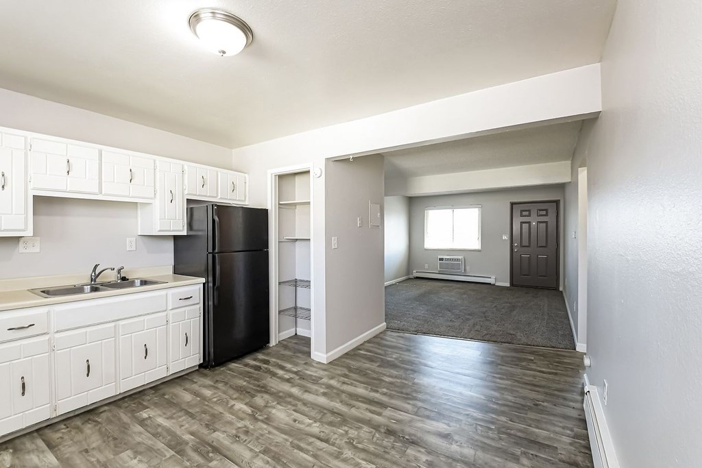 A kitchen with white cabinets and a black refrigerator.