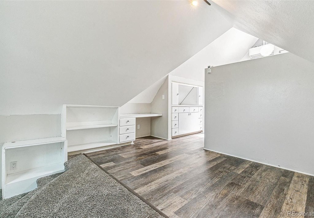 A room with a desk and drawers in the corner.