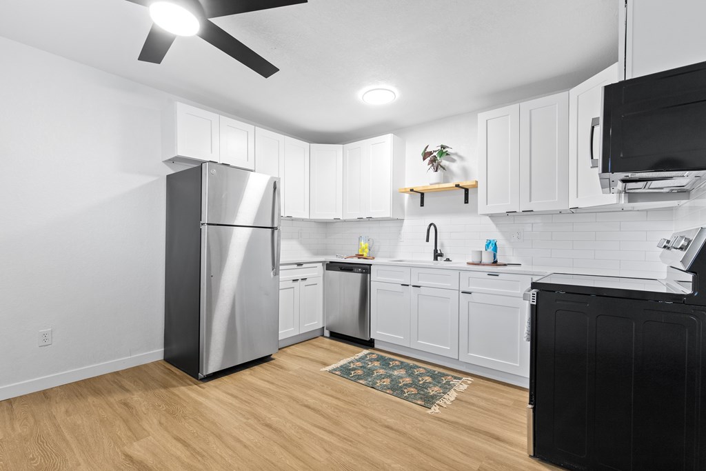 A kitchen with a black fridge and a black dishwasher.