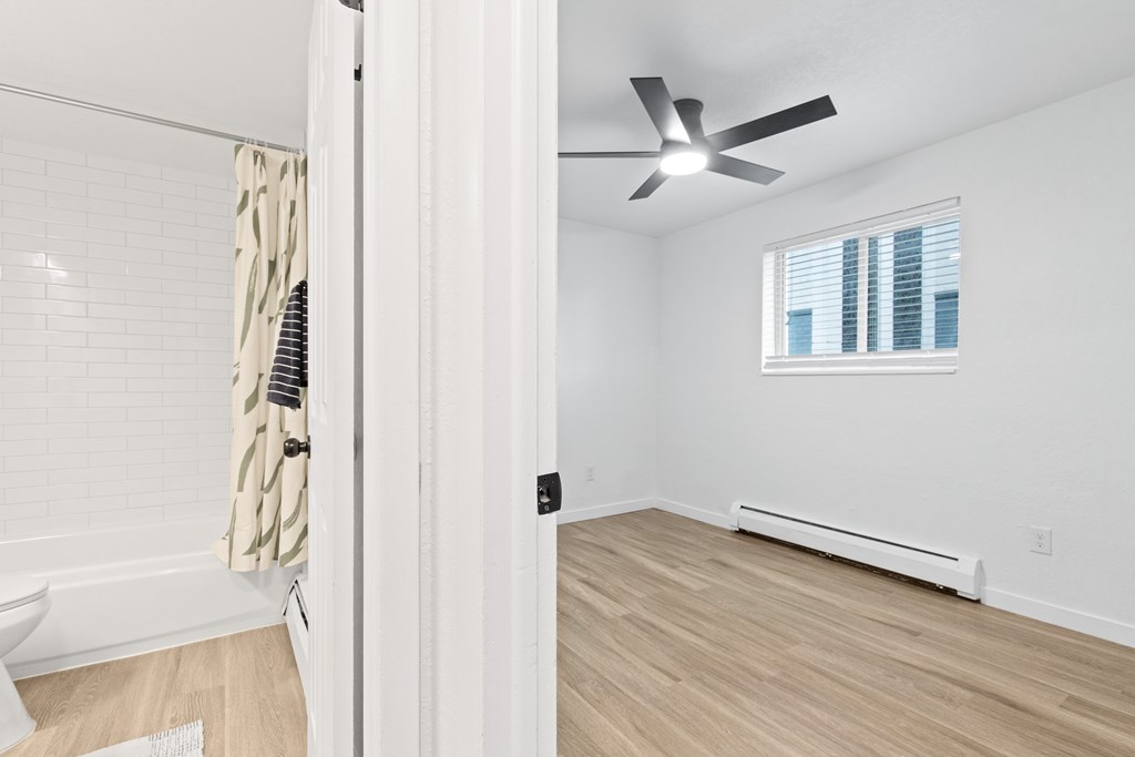 A room with a ceiling fan and a window with blinds.