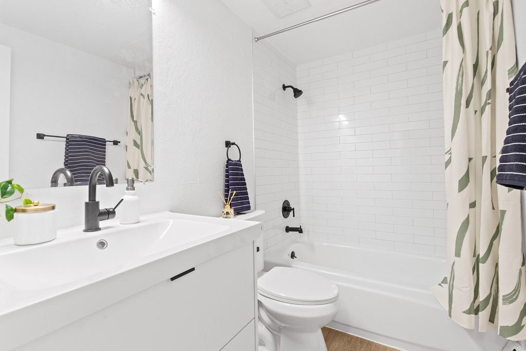 A white bathroom with a toilet, sink, and shower.