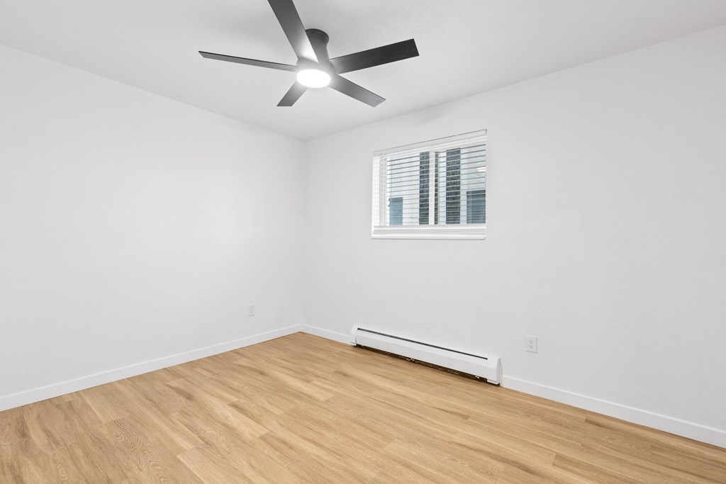 A room with a ceiling fan and a window with blinds.
