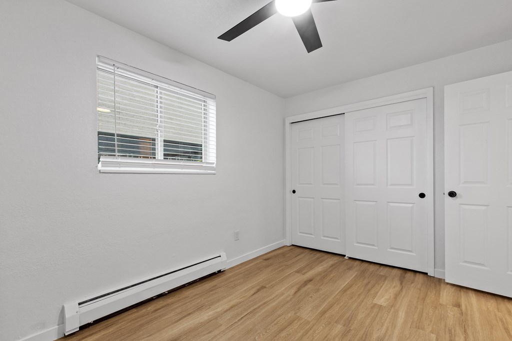 A room with a ceiling fan and two doors.