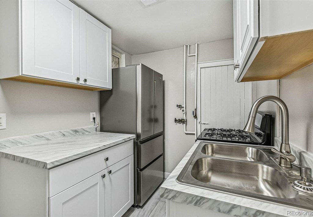 A kitchen with a sink, refrigerator, and cabinets.