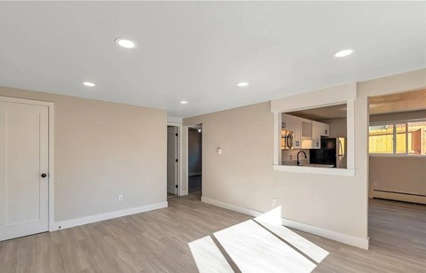 A spacious room with a white rug on the floor and a television in the corner.