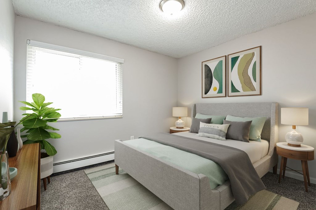 A bedroom with a bed, two lamps, and a potted plant.