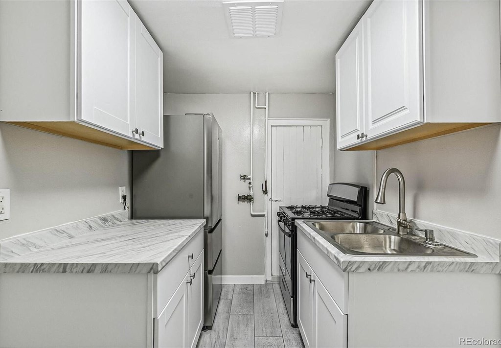 A kitchen with white cabinets and a marble countertop.