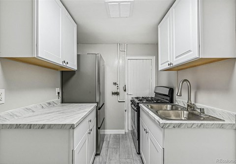 A kitchen with white cabinets and a marble countertop.