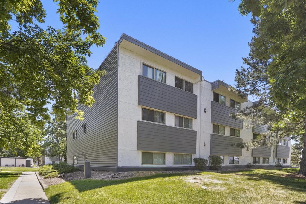 a white and gray apartment building with grass and trees at The Iris Apartments, Arvada, Colorado