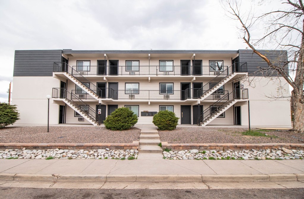front view of an apartment building with stairs and a sidewalk