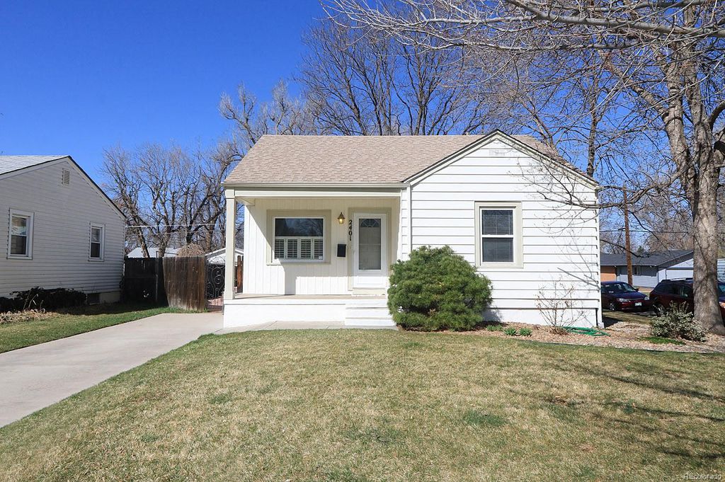 A white house with a brown roof and a small front yard.