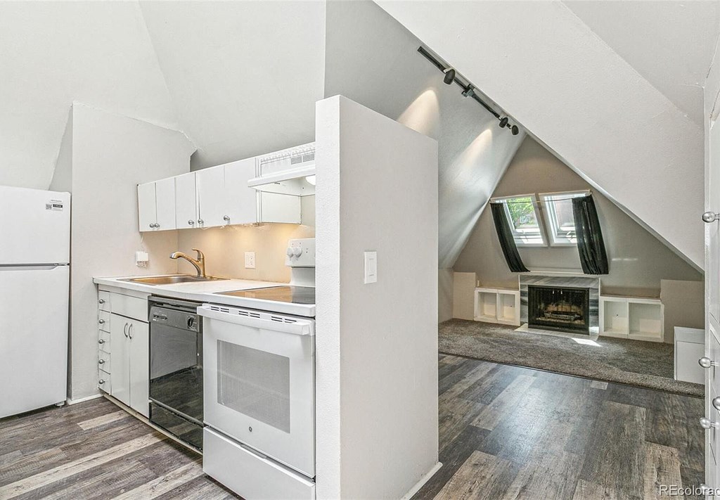 A modern kitchen with white appliances and a wooden floor.