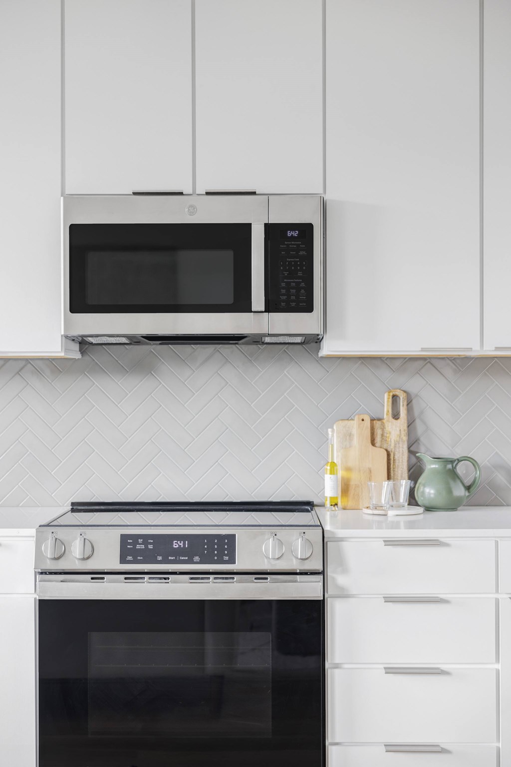 A modern kitchen with a microwave above an oven and white cabinets.
