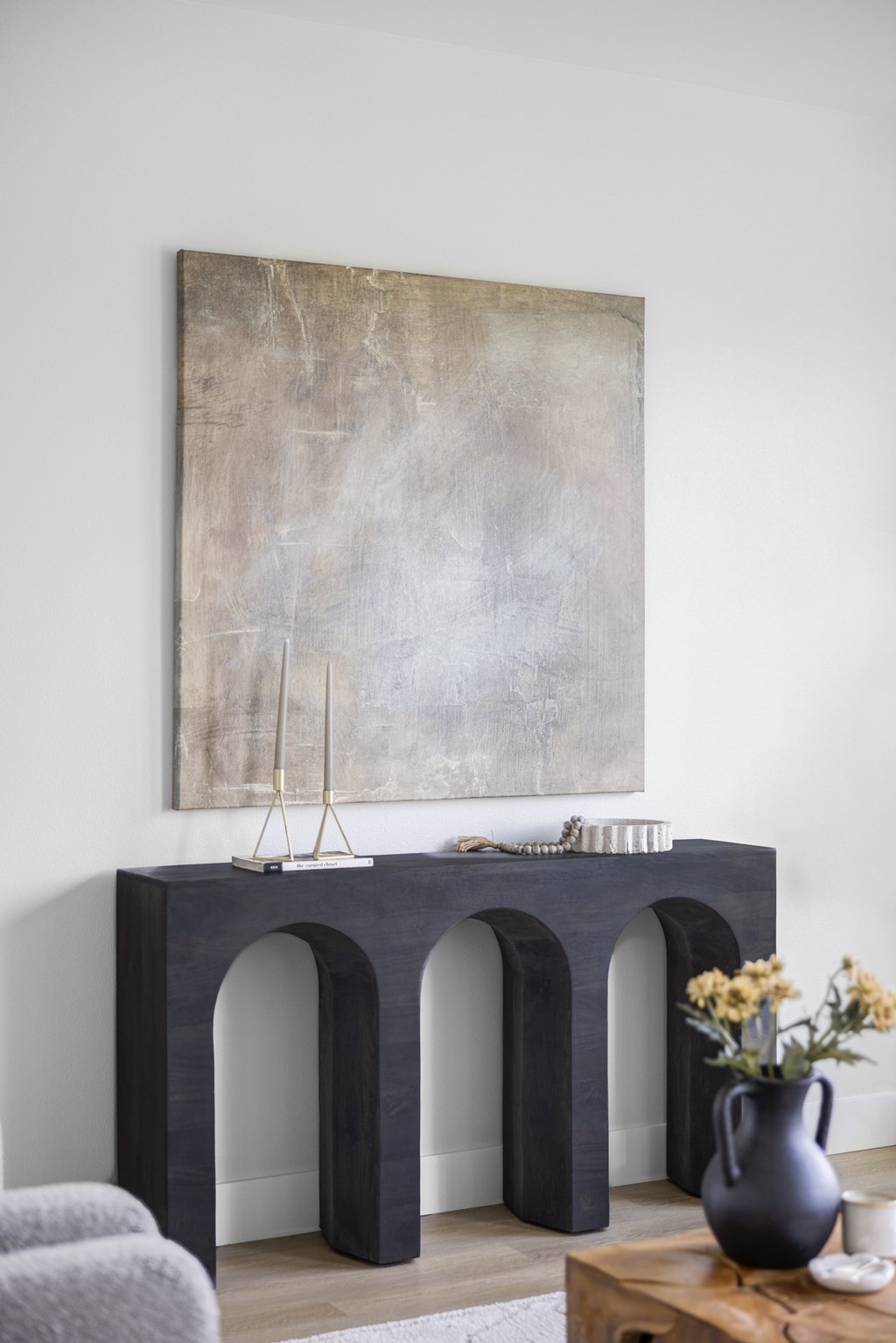 A grey sofa sits in front of a large grey and white painting.