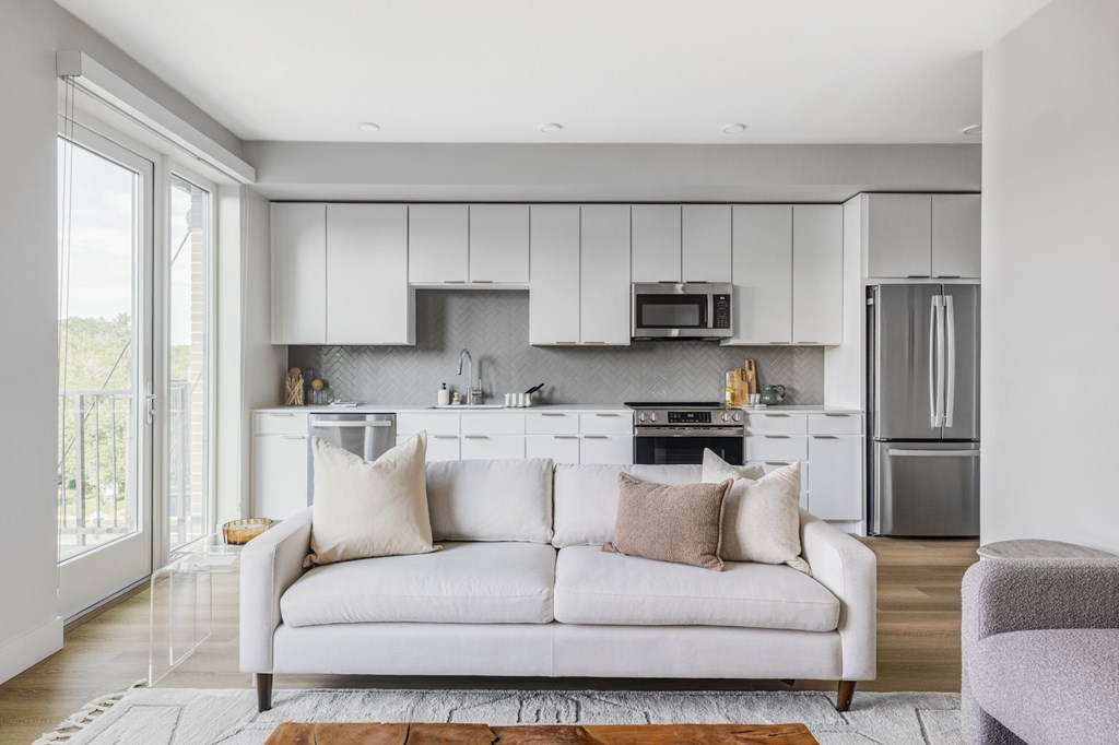 A modern kitchen with a white couch and a grey armchair.