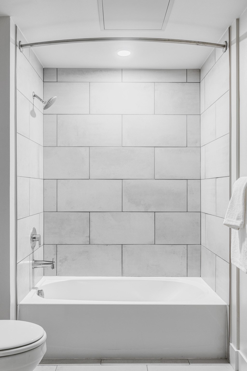 A white bathroom with a tub, toilet and a towel.