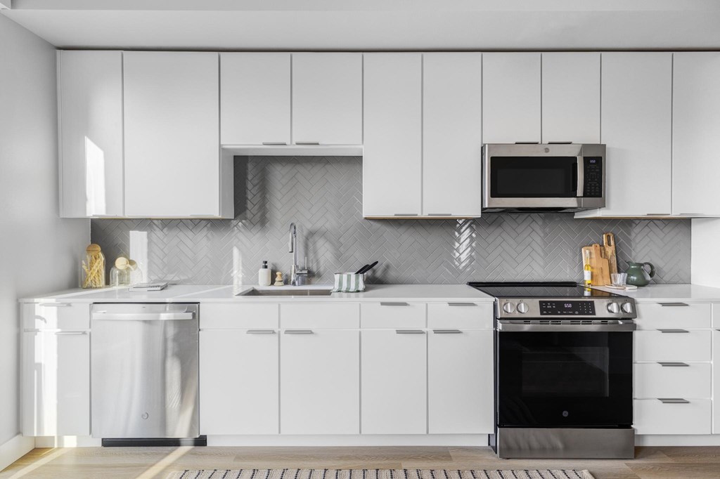 A modern kitchen with white cabinets and stainless steel appliances.