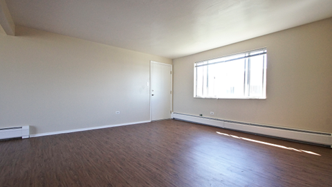 an empty living room with wood floors and a window