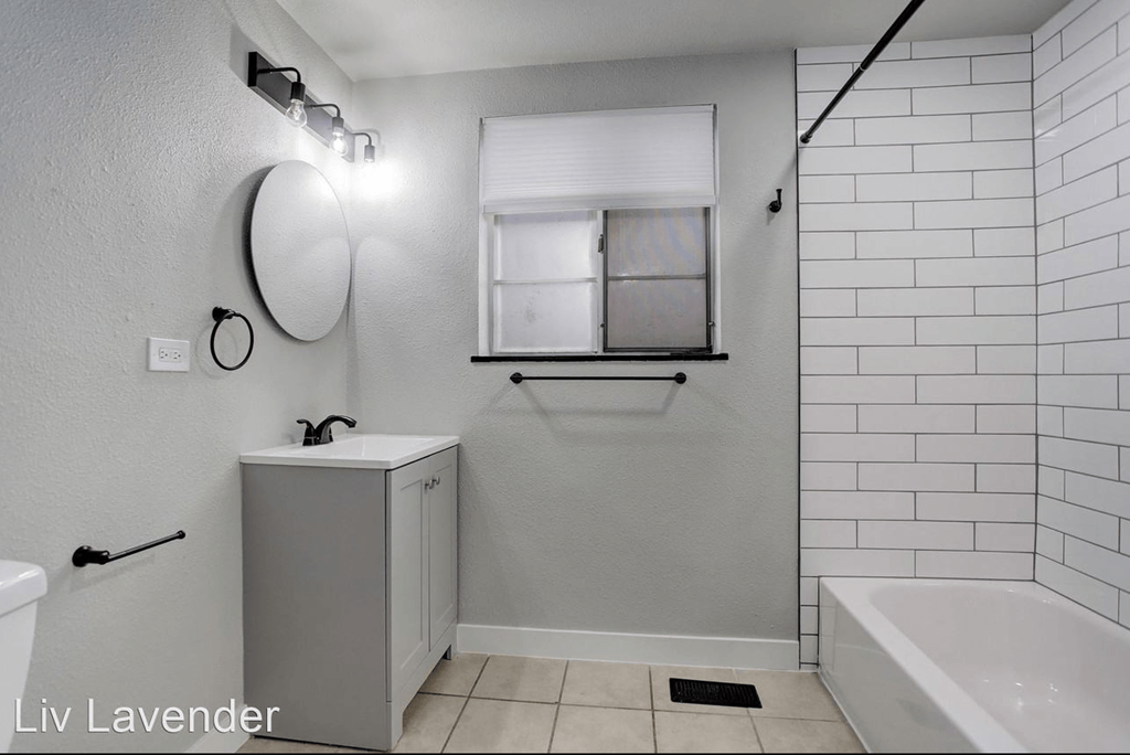 a white bathroom with a sink and a tub and a window