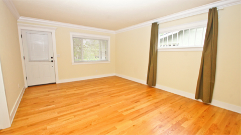 a living room with a hard wood floor and a white door and curtains