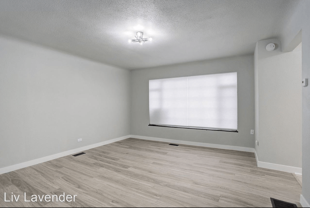 a living room with a large window and wood flooring