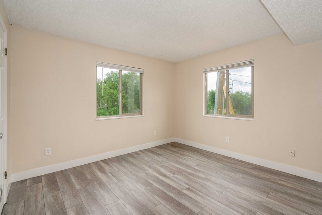 an empty living room with wood floors and two windows