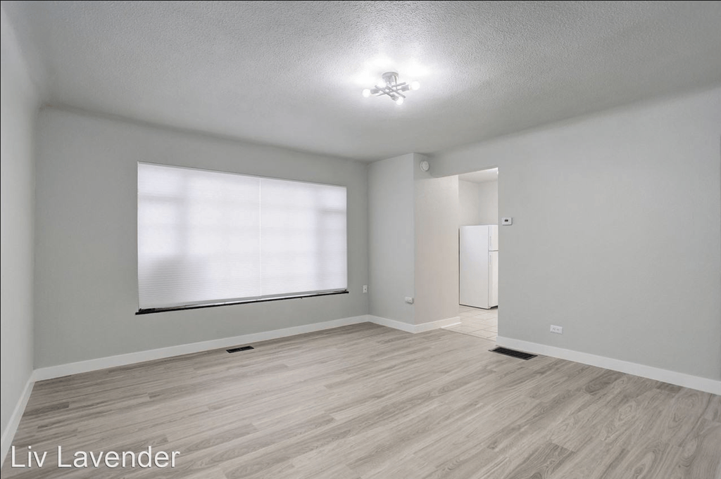 the living room and dining room with a large window and wood flooring