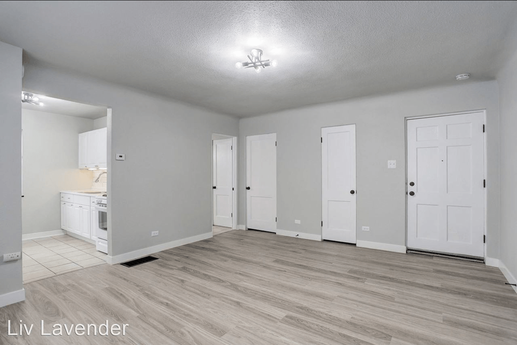 a living room and kitchen with white doors and wood flooring