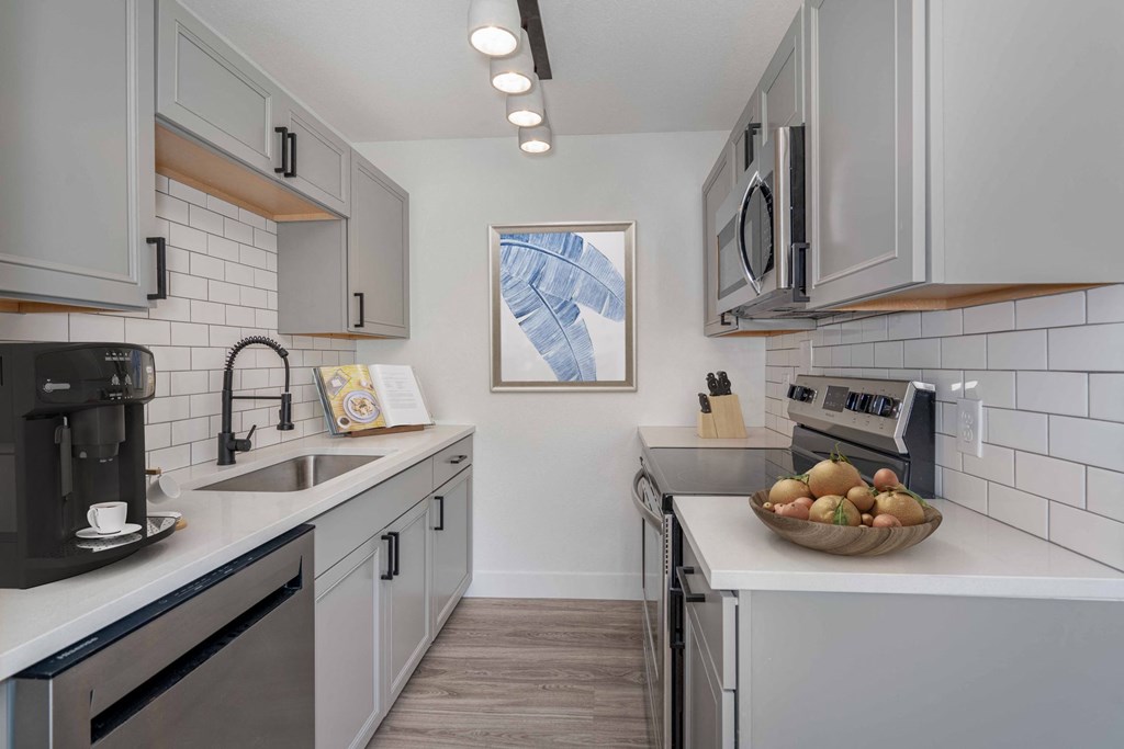 a kitchen with white cabinets and stainless steel appliances and a bowl of fruit