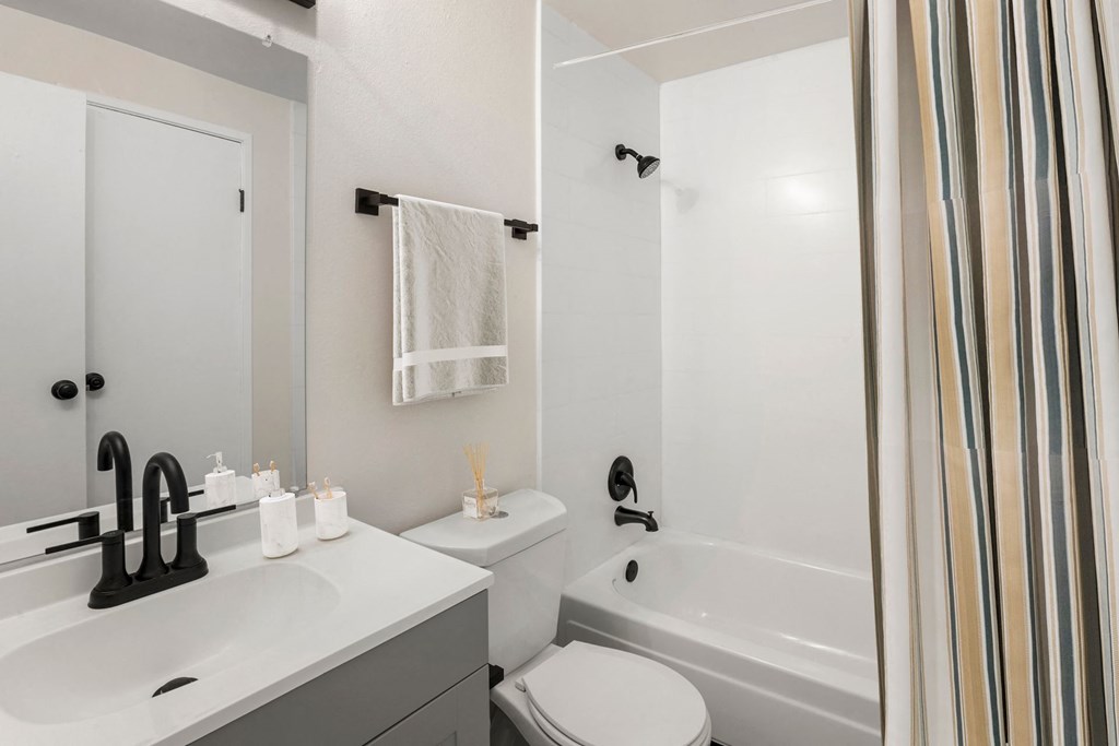 a white bathroom with a shower and a toilet and a sink at The Iris Apartments, Arvada, Colorado
