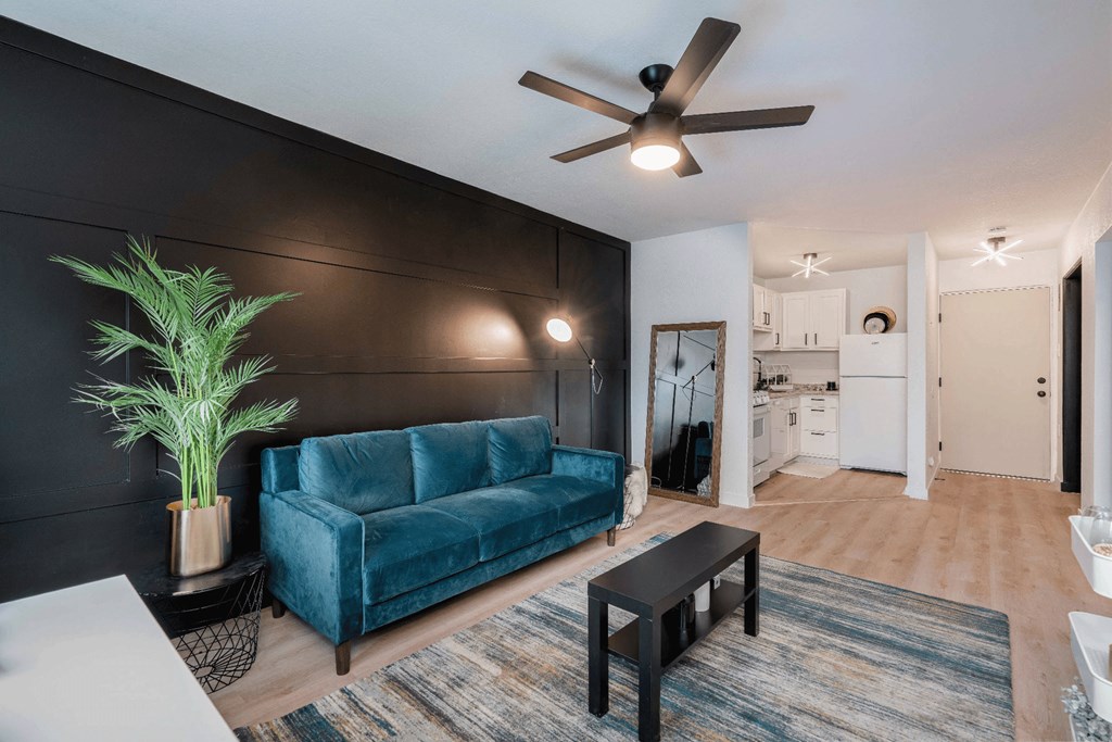 a living room with a blue couch and a ceiling fan