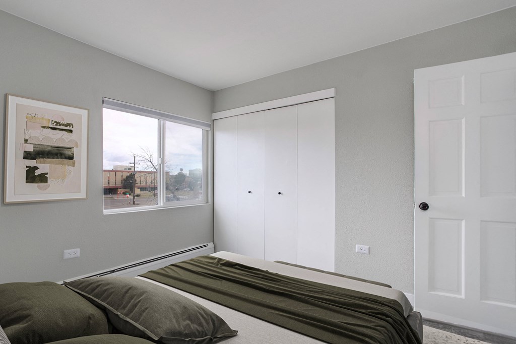 an empty bedroom with a bed and two windows