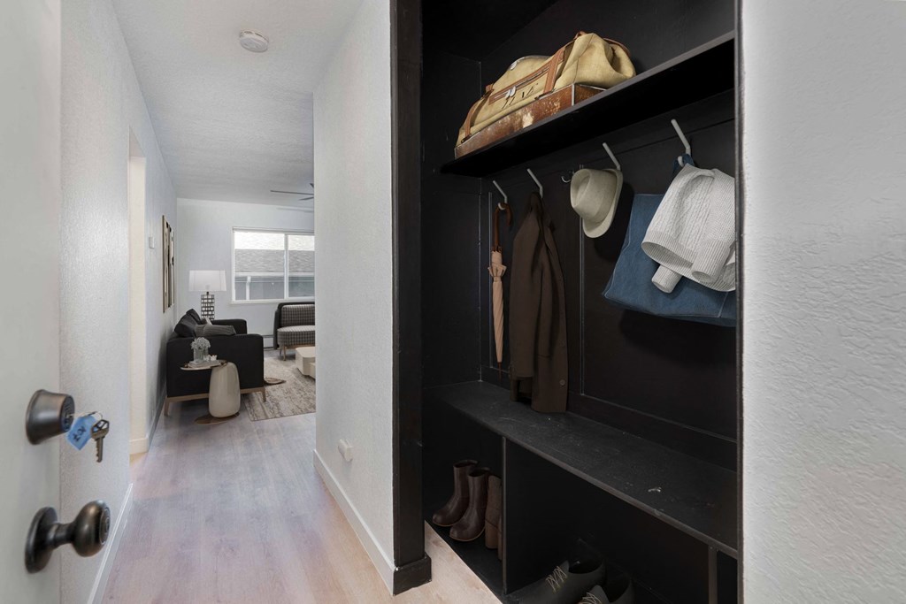 a walk in closet with a black wall with jackets and shoes on it