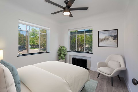 A white couch sits in a living room with a ceiling fan and a chair.