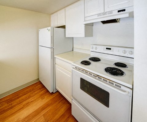A white stove and refrigerator in a kitchen with wood floors.