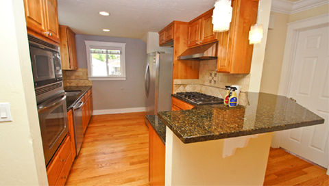 A kitchen with wooden cabinets and a granite counter top.