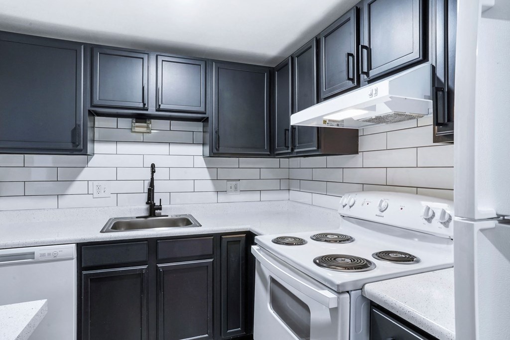 a kitchen with white appliances and black cabinets at The Iris Apartments, Arvada, CO