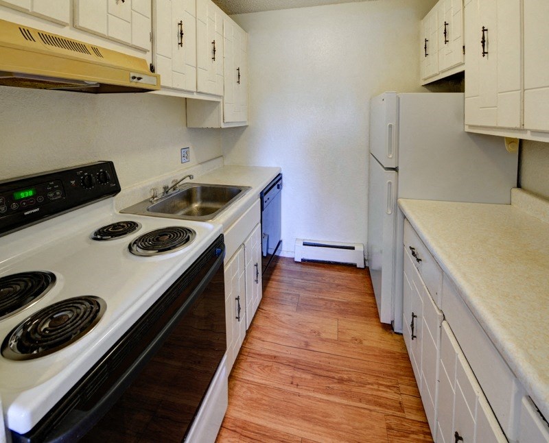 A kitchen with a white stove and wooden floors.