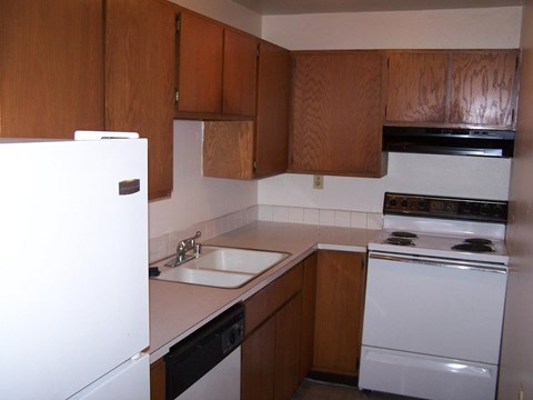 A kitchen with brown cabinets and white appliances.